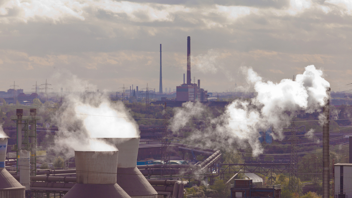 Vy över industri med rykande skorstenar.